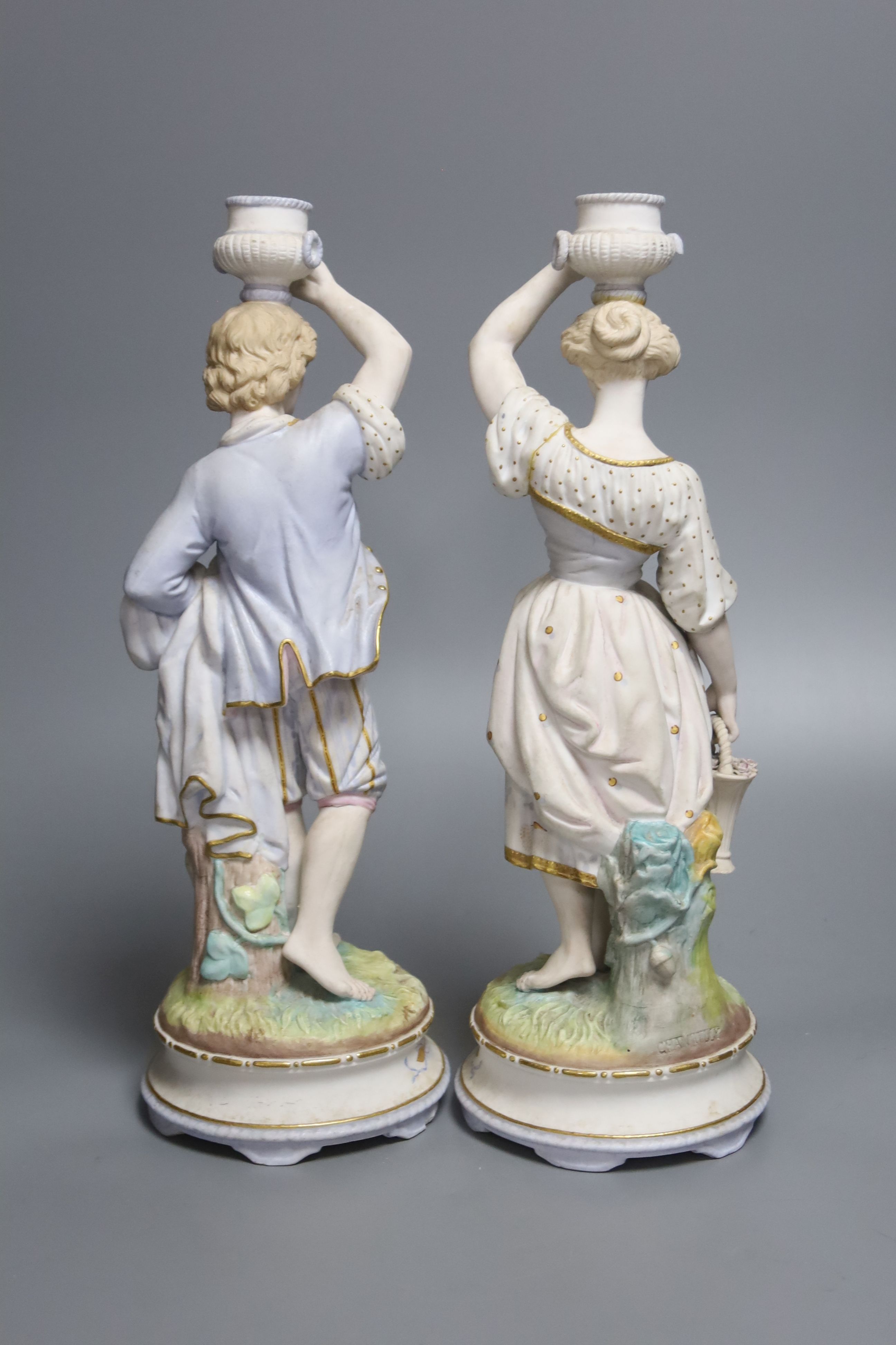 A pair of French export bisque porcelain figural candlesticks, stamped Chantilly, height 34cm (one damaged)